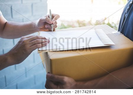 Delivery Mail Man Giving Parcel Box To Recipient And Signature Form, Young Owner Signing Receipt Of 