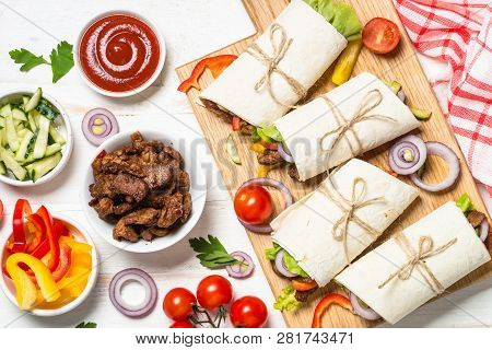 Burritos Tortilla Wraps With Ingredients - Beef And Vegetables On White Table.  Traditional Latin Am