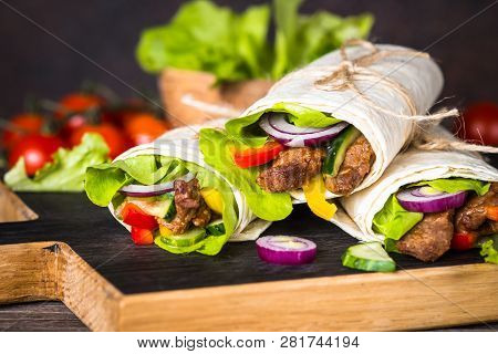 Burritos Tortilla Wraps With Beef And Vegetables On Wooden Cutting Board. Traditional Latin American