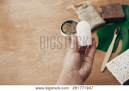 Hand Holding Natural Eco Alunite Deodorant On Background Of Bamboo Toothbrush, Soap, Solid Shampoo,