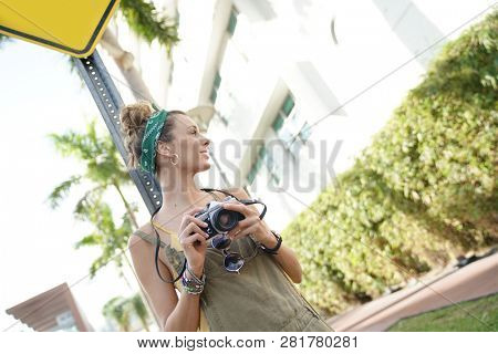Stylish young woman with vintage camera in urban setting
