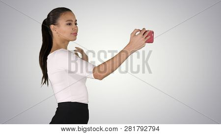 Pretty Girl Taking A Selfie And Walking On Gradient Background.