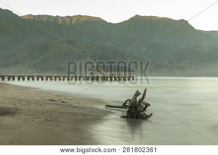 Sunrise Lights Driftwood On Hanalei Bay With The Na Pali Coast In The Background Near Hanalei, Kauai