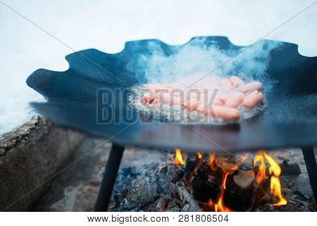 Cooking Sausages In A Flat Pan On The Bonfire Outdoor Of Winter