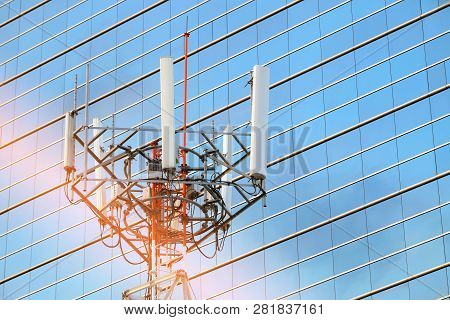 Cellular Network Antenna With Background Of Windows Of High Building And Beautiful Sunlight