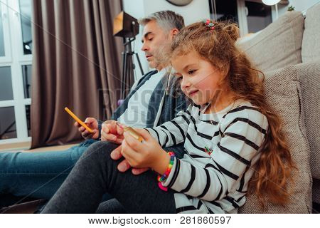 Pretty Small Red-haired Girl In A Striped Sweater Polishing Her Nails