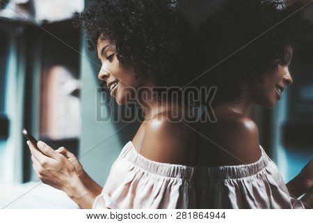 A Drop-dead Gorgeous African-american Girl With A Medium Curly Afro Hair Outdoors Is Leaning Against