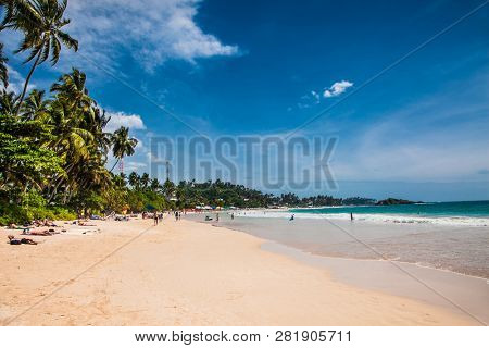Mirissa Beach, Sri Lanka - JAN 2, 2017:  Tourists walking on the sand while enjoying the view across the wonderful beach of Mirissa on Jan 2, 2017. Sri Lanka.