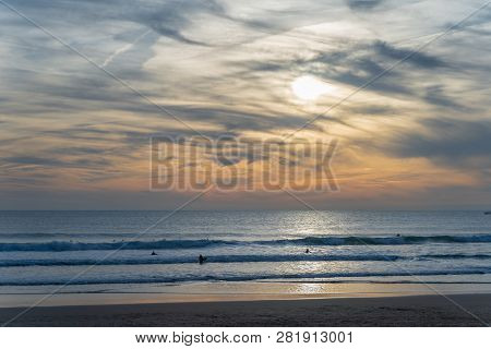 Carcavelos Beach, One Of The Most Famous Lisbon Beaches, At Sunset During Winter, With Many Surfers 