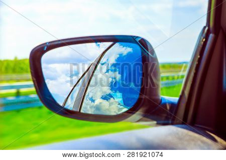 Blue Sky With Clouds In The Sideview Mirror Of A Car, On Road Countryside. Travel Natural Advanture 