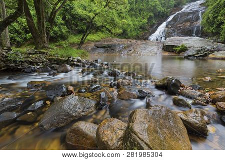 River Flowing Over Wet Rocks And The Debengeni Waterfall
