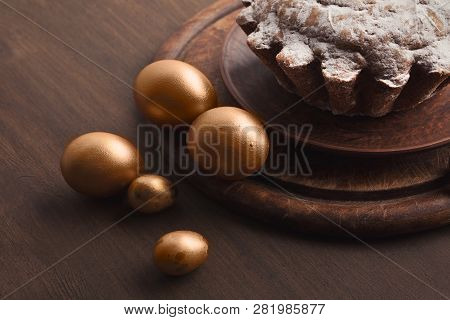 Coloured Golden Eggs And Easter Cake With Powder On Wooden Table