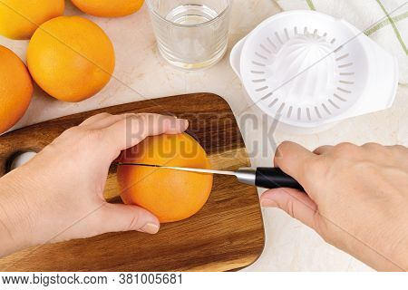 Caucasian Woman Hands Cut Ripe Orange In Half To Make Freshly Squeezed Juice With Plastic Manual Cit