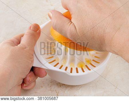 Caucasian Woman Hands Squeeze Juice From Ripe Sweet Orange Using Plastic Manual Citrus Juicer On A K