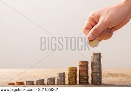 Hand Putting Coins On Stack On Real Wood Table,saving Money Concept Or Business Growth Concept