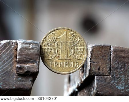 Hryvnya Coin Clamped In A Metal Vise. Currency And Ukrainian Economy Under The Onslaught, The Concep