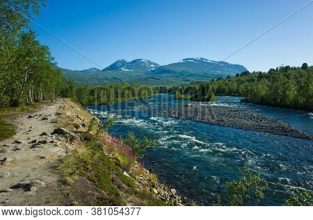 Nature of Scandinavia in summer. Hiking trail lays along Abiskojokk river in Abisko National Park in northern Sweden. Sunny day
