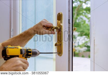 Professional Locksmith Installing Or New Lock On A House Door Handle With Screwdriver