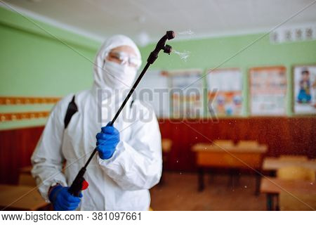 Close Up Of A Spray With Sanitizing Liquid In The Hands Of A Man Wearing A Protective Suit In The Sc
