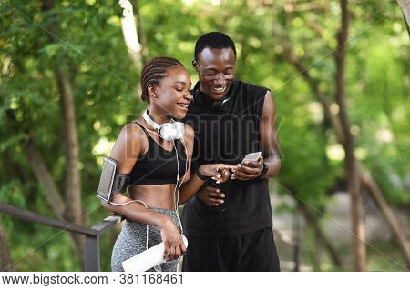 Excited Black Couple Checking Burned Callories After Training Outdoors With Smartphone App, Enjoying