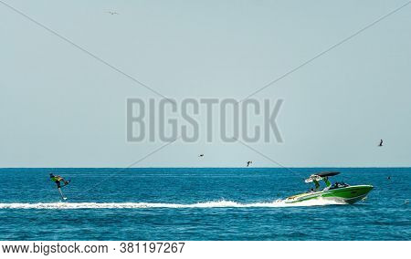 Silhouette Of Motor Boat And Wakeboarder Jumping Crazy Trick. Wakeboarder Making Tricks On The Sea P