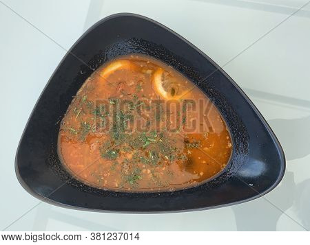 A Plate Of Hodgepodge On A White Table. First Dish With Meat And Vegetables. Soup With Herbs And Lem