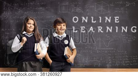 Schoolchildren in unifirm with books and backpacks in front of a blackboard with text online learning 