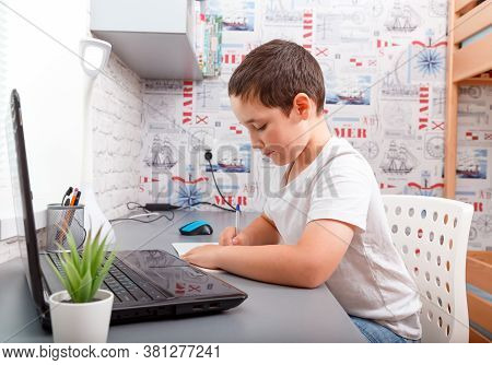 Happy Caucasian Schoolboy Doing Homework Sitting At Desk, Teen Boy Feels Glad Studying Online E-lear