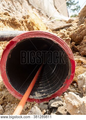 Detail Of Optic Fiber Wire In Ribbed Flexible Red Plastic Tube, Thin Trench At Lamp Post