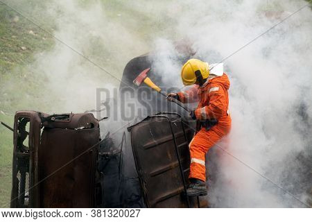 Firefighters Using Ax Destroy Obstacles In A Burning And Smoky Car.