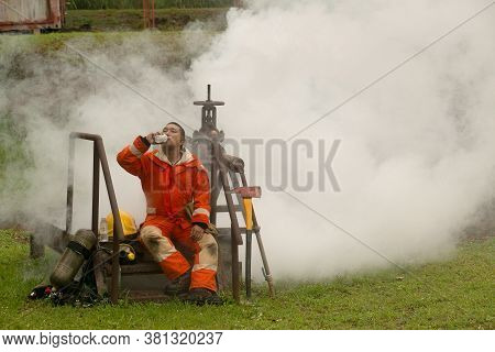 The Firefighters Drink Water While Resting. After The Fire That Burned The Car Behind.