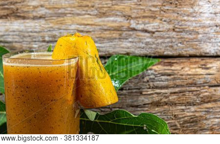 Papaya Juice In A Setting With Fresh Fruits On A Wooden Background.