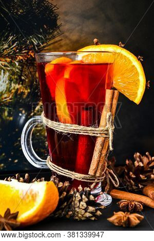 Mulled Wine Hot Christmas Drink With On A Dark Background. Orange Slices, Cinnamon Sticks, Christmas