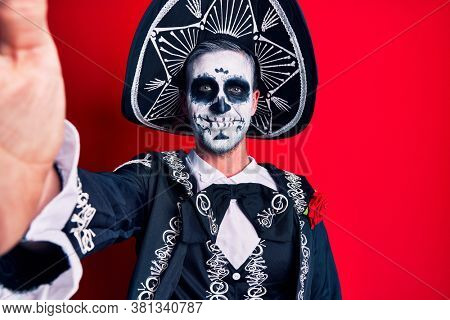 Young man wearing mexican day of the dead costume make selfie by the camera looking positive and happy standing and smiling with a confident smile showing teeth 