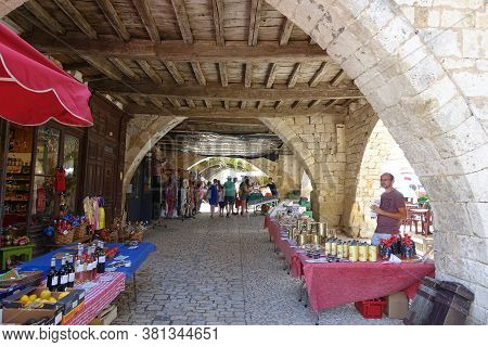 Monpazier, France 09 July 2020: Market Stalls Set Up Under The Medieval Arches In The Town Of Monpaz
