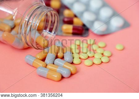 Pills On Pink Background, Variation Of Medication In Capsules And Tablets Scattered From A Bottle. C