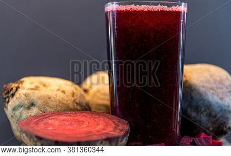 Glass With Beet Juice (beta Vulgaris) And Tubers On Wooden Board
