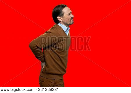 Adult Man Suffering From Backache On Red Background. Side View Unhappy Mature Man Suffering From Bac