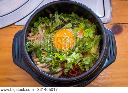 Top View Of Bibimbap, Traditional Korean Food Served In Warm Bowl And Cooked By Mixed Rice With Vege