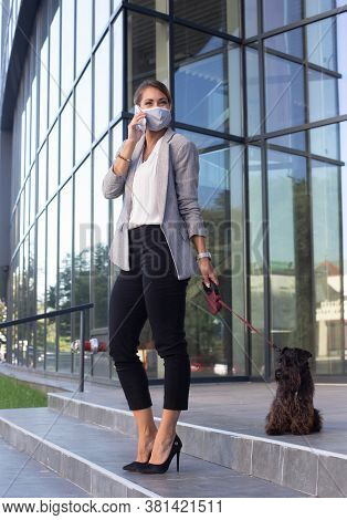 Attractive Young Business Woman Talking On Mobile Phone In Front Of Office Building And Walking Dog 
