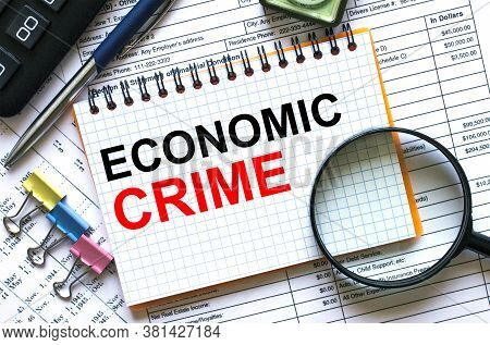 Text Economic Crime On Notepad With Calculator, Clips, Pen On Financial Report
