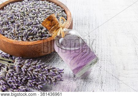 Glass Bottle Of Lavender Essential Oil With Fresh Lavender Flowers And Dried Lavender Seeds On White