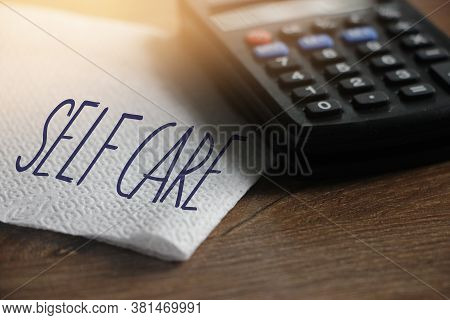 Self Care Words On Napkin And Calculator On Wooden Table. Healthcare Concept