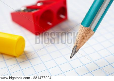 Pencil, Sharpener And Felt-tip Pen Close-up On The Background Of A Squared Notebook Sheet. Illustrat