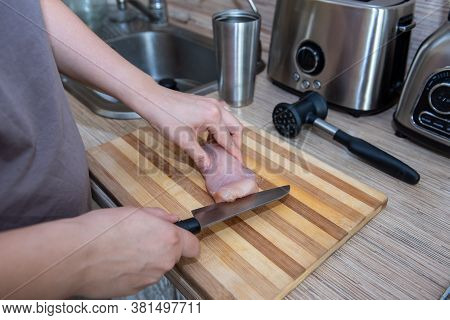 Female Hands Cut Chicken Fillet On Wooden Board With A Knife