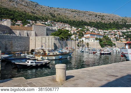 Boats Moored In Dubrovnik Harbour By The City Walls Of The Old Town And Srd Mountain, Croatia