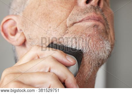 Senior Man With Untrimmed Stubble Beard Shaving With Trimmer Or Electric Shaver.