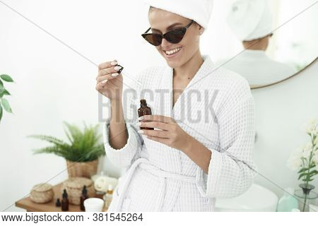 A Cute Young Woman Moisturizes Her Skin With Her Hylauron Serum In Her Bright Bathtub. A Young Woman