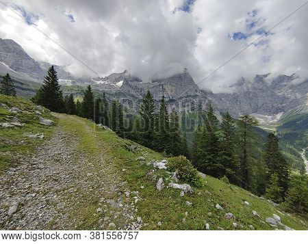 Summer Alpine Mountain Rural Landscape. View Over Green Meadow, Forest, Snow Covered Alpen Mountain 