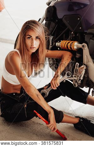 Dangerous Looking Young Girl With Wrenches Posing In A Photo Studio With A Sports Motorcycle